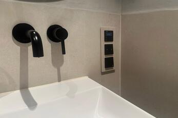 Eine Badezimmerarmatur auf der die Schalter in Wandoptik eingefasst sind